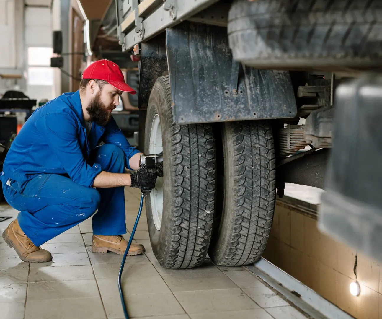 Mechanic inflating truck tire in workshop.